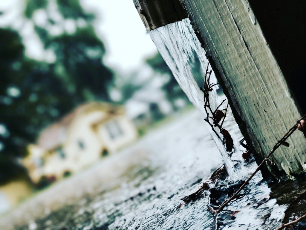 Close-up of rainwater flowing from a gutter during a storm, capturing the essence of rainy weather.